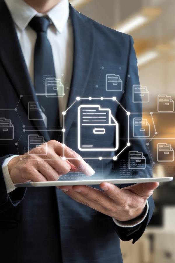 Person in a suit holding a tablet with a security shield icon